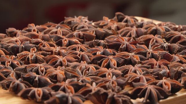 Cinematic ground level macro perspective of dried star anise spices on a wooden board. Aromatic background for culinary and herbal medicine concepts.