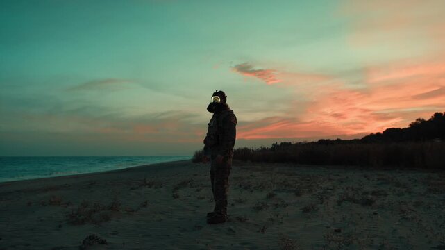 Soldier in silhouette at sunset on a beach contaminated by a nuclear attack