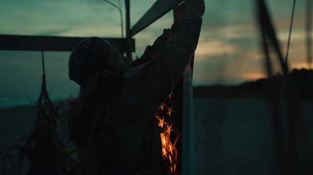 American soldier collects a flag at night on the beach at sunset