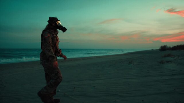Soldier walks on beach contaminated by radiation from nuclear attack at sunset