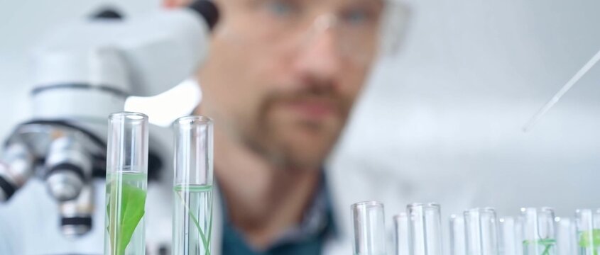 Man researcher with safety glasses is working with lab tubes using a pipette in laboratory, close-up of lab equipment. Science and medicine