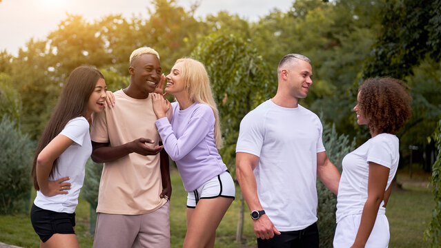 Multi-ethnic group teenage friends. African-american asian caucasian student spending time together Multiracial friendship Happy smiling People dressed black white sportswear meeting outdoor