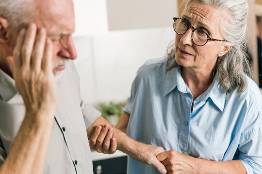 Senior woman comforts her distressed husband suffering from headache