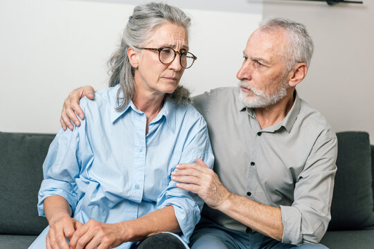 Senior man comforts sad woman during difficult conversation at home