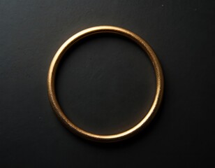 Obraz premium Golden circle bangle lays on dark textured surface. Minimalist jewelry piece shines with subtle light reflection. Smooth shiny metal round accessory isolated studio shot.