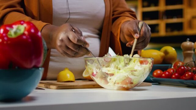 Close up of influencer chef mixing fresh salad ingredients in a bowl, filming meal prep for culinary vlog. Female content creator following the cooking process and recording video for audience.