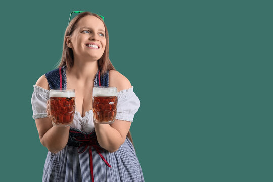Redhead Irish waitress with beer on green background. St. Patrick's Day celebration