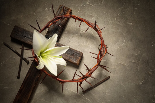 Wooden cross, crown of thorns, nails and lily flower on grey grunge background. Good Friday concept