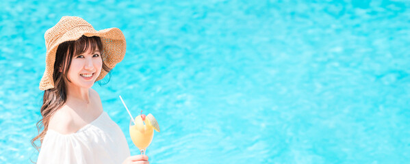 A young Asian woman drinking tropical juice by the poolside (resort, vacation)