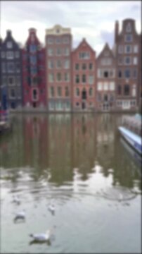 Flower basket with seagulls and blurred canal houses on Damrak in Amsterdam, Netherlands