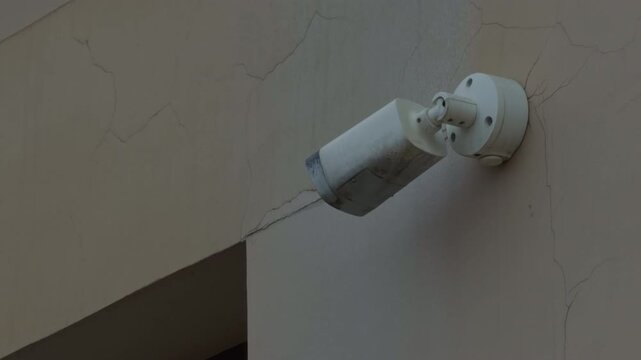 Outdoor surveillance camera with cylindrical design capturing realtime footage of building entrance and surroundings