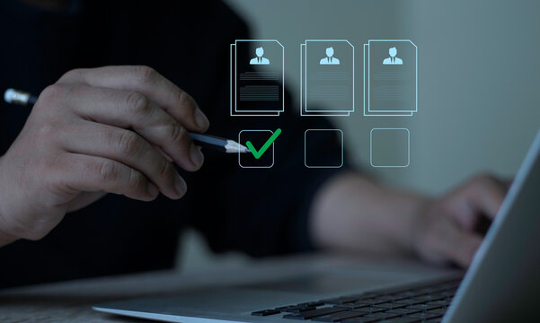Evaluation and approval process. A professional checks candidate profiles and approves the selection with a green check mark on a digital laptop interface.