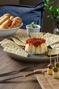 A table with a sweet red pepper and cream cheese sauce called "chismosa," olives, and teque&ntilde;os to share with family and friends. Cream cheese with red pepper sauce, a Venezuelan recipe