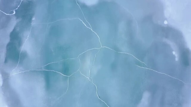Aerial view of frozen water surface with visible cracks patterns and textures highlighting natural ice formation and winter landscape