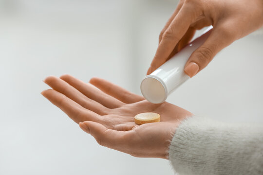 Young woman taking vitamin C soluble tablet from bottle at home