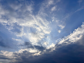 Fototapeta premium 雲の間から差し込む朝の光と青空に広がる白い雲