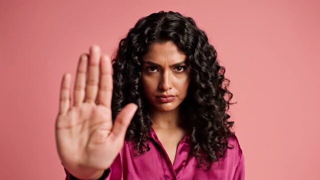 Woman with curly hair makes a stop gesture with her hand
