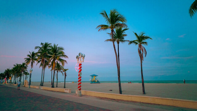 Hollywood Beach boardwalk at dusk with decorated lamp posts and palms. Festive evening holiday atmosphere in Florida.