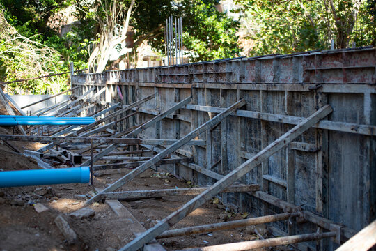 Concrete formwork with metal supports at construction site. Reinforced structure prepared for pouring foundation wall.