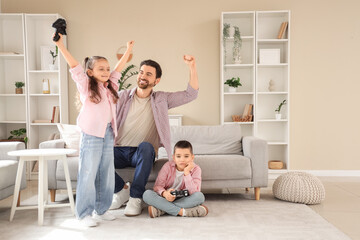 Fototapeta premium Happy father with his little children playing video game at home