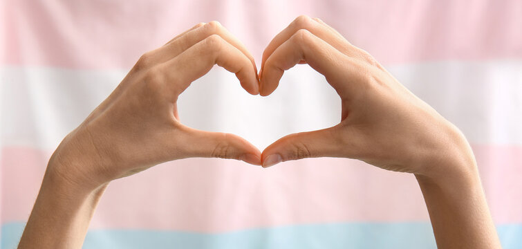 Female hands in shape of heart and transgender flag