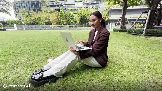 Girl enjoy listening music and reading a book and play laptop on the grass field of the park in the morning (greenery tone),Woman using tablet in park on a sunny day