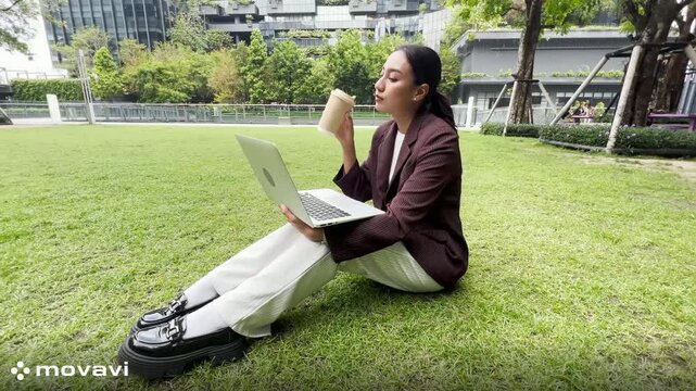 Girl enjoy listening music and reading a book and play laptop on the grass field of the park in the morning (greenery tone),Woman using tablet in park on a sunny day