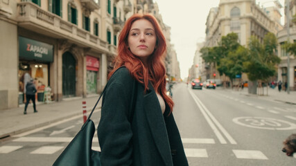 Obraz premium Red-Haired Woman Walking On City Street Fashion Style