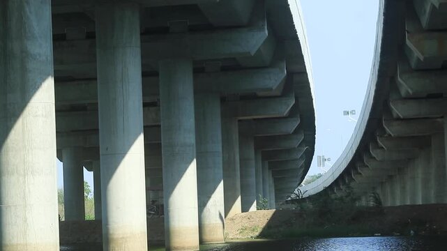 A tall concrete bridge over a river in the city with blue sky and surrounding buildings
