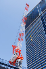 Fototapeta premium 建設中の高層ビルと赤白のタワークレーン