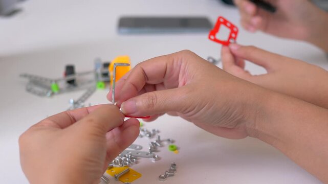 Close up of child hands assembling 3D printed robot model on table. Concept of STEM education, robotics learning, creativity, and technology development