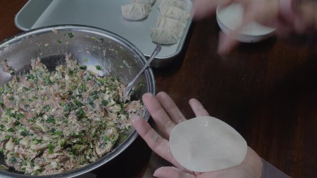 餃子の具材(キャベツ・にら・豚ひき肉)を皮に包む｜餃子を作る　イメージ