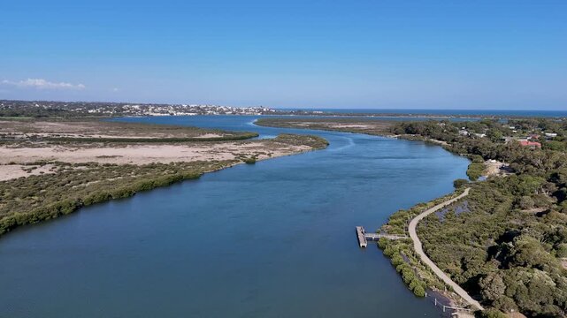 Aerial view of Barwon River near Barwon Heads, Victoria, Australia, with winding water channels leading toward the ocean, waterfront trail and fishing jetty.  Natural landforms and coastal vegetation