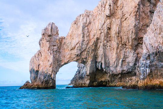 Massive sea cliff arches over turquoise ocean waters