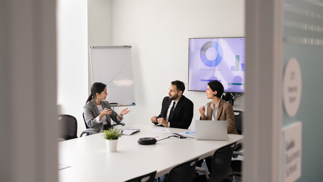 Diverse business executives discussing financial strategy, collaborate on project, listen team leader presenting idea, solution or point during formal meeting in office boardroom. Strategic planning
