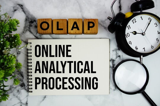 OLAP Online Analytical Processing text with alarm clock and magnifying glass on marble background