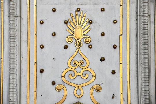 A classic architectural detail featuring gold leaf decoration with elegant curves and palmette motifs