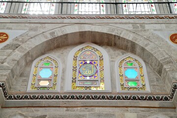 Obraz premium The stained-glass windows of the historic Mihrimah Sultan Mosque in Istanbul, featuring the name of Allah in the central panel