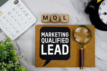 Naklejka premium MQL Marketing Qualified Lead text with calculator, magnifying glass and alarm clock on marble background