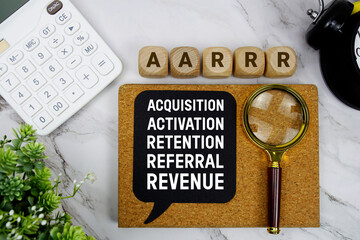 Naklejka premium AARRR Acquisition, Activation, Retention, Referral, Revenue text with calculator, magnifying glass and alarm clock on marble background