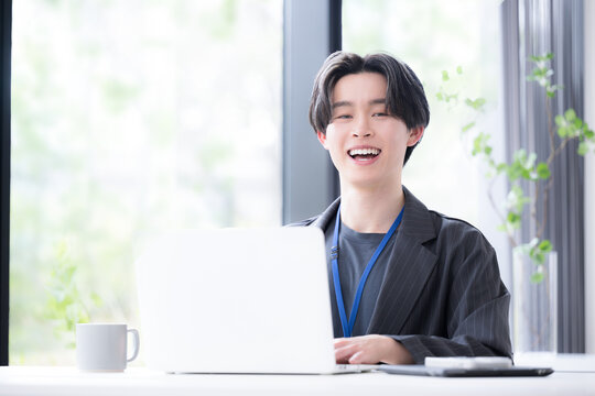 パソコンに向かう若いビジネスマンカメラ目線　若手社員の爽やかな成長と成功のビジネスシーン
