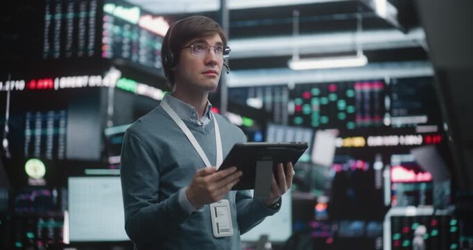 Successful Financial Analyst Surveying Real Time Trading Floor. Young Trader Stands in of High Tech Stock Exchange, Wearing Professional Headset and Corporate Lanyard. Concept of Top Tier Competence.