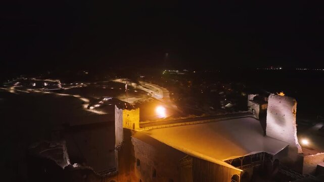 Aerial view rotating around the Estonian flag on the Rakvere Castle, winter night