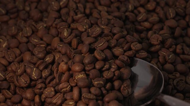 Slow motion shot of a spoon picking up and dropping coffee beans