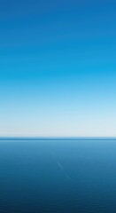 Fototapeta premium A perfect, empty horizon line dividing the vast blue sky above from the flat, featureless water or land below. Minimalist and serene, natural, purity, sky