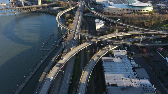 4K aerial drone view of I 5 and I 84 interchange in downtown Portland Oregon USA near Willamette River with freeway ramps, traffic, convention center and moda center in morning light