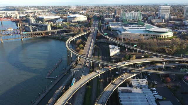 4K aerial drone view of I 5 and I 84 interchange in downtown Portland Oregon USA near Willamette River with freeway ramps, traffic, convention center and moda center in morning light