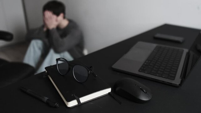 Remote work frustration and burnout, desk in focus and blurred man overwhelmed in home office