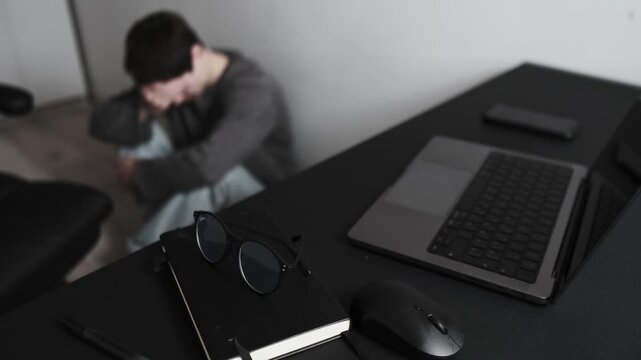 Young man overwhelmed by work pressure, early burnout and lost motivation, sitting on floor at home office, frustrated generation lifestyle