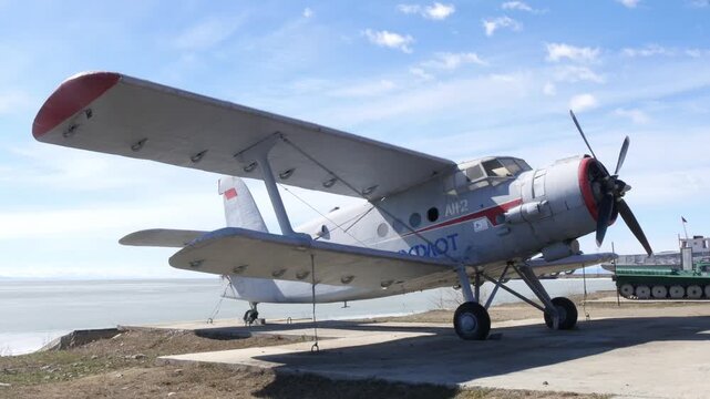 NIZHNEANGARSK, RUSSIA - MAY 10, 2025: A small AN-2 aircraft is temporarily parked in a small Siberian town against the backdrop of the ice-covered Lake Baikal in late spring.